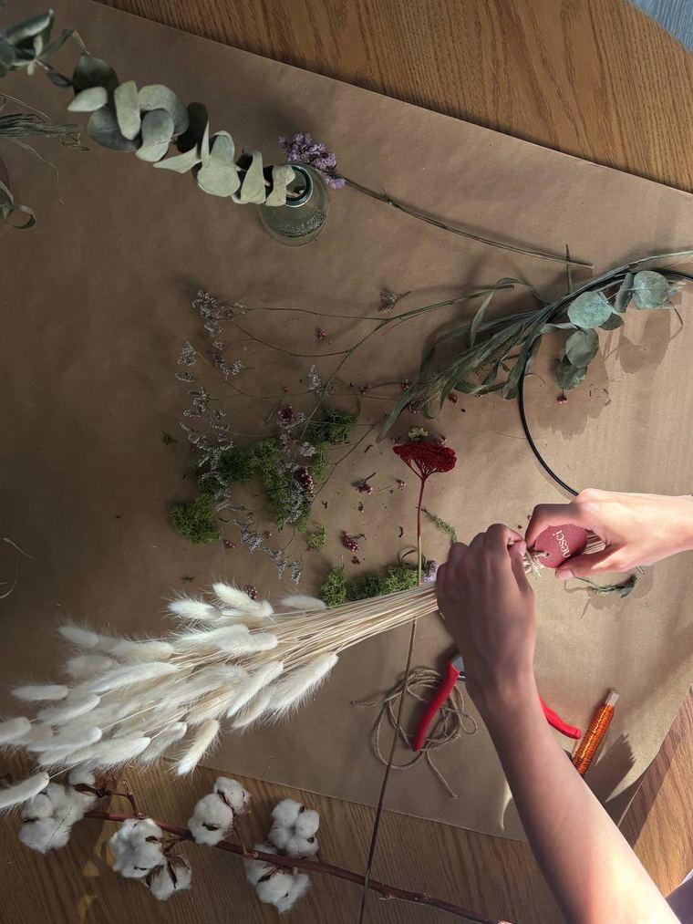 Mani che compongono un mazzo di fiori essiccati